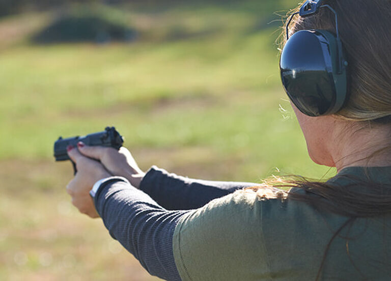 Shooter wearing Passive Slim Fit Ear Muffs aiming pistol